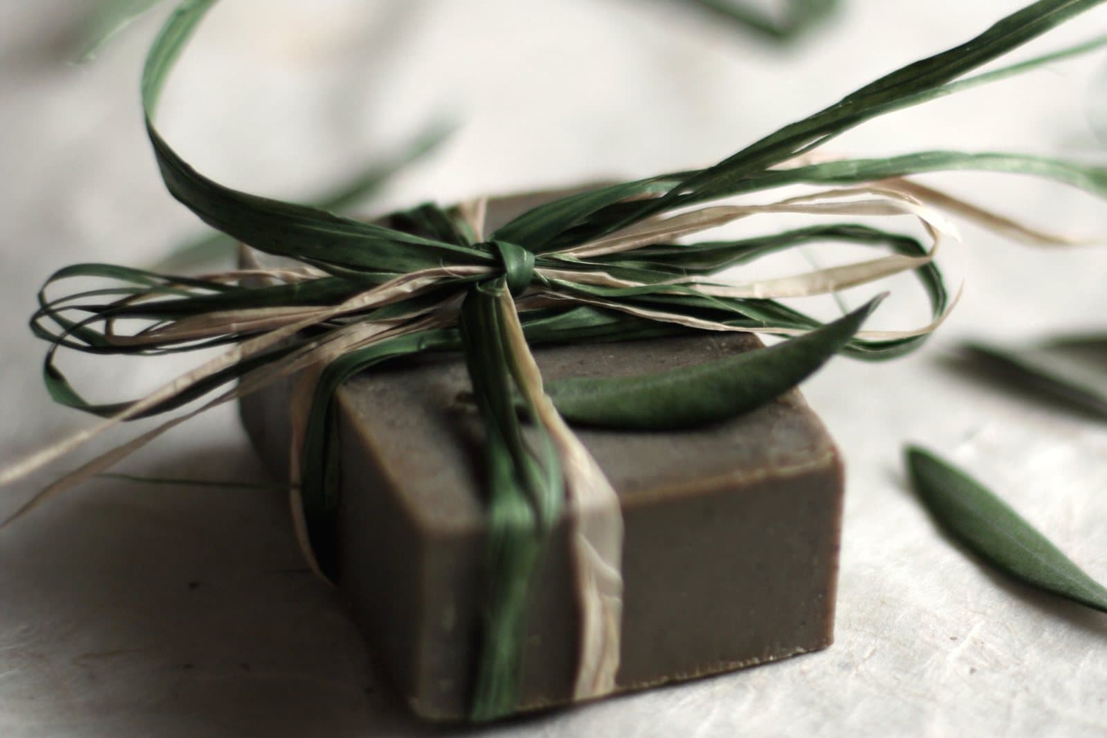 A bar of natural soap tied with greenery on a pale surface
