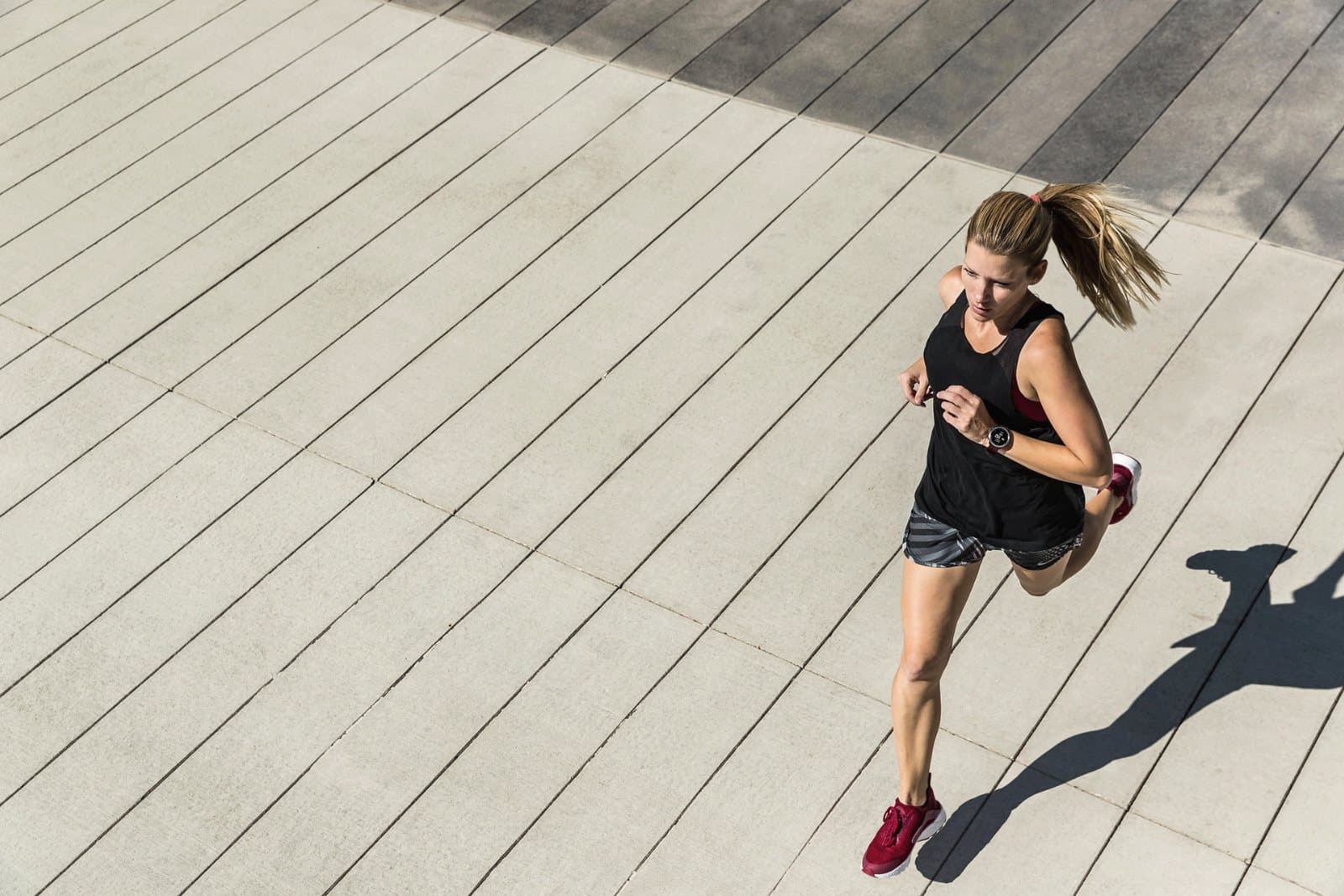 A runner mid stride on a boardwalk, seen from above